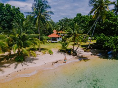 Asyalı kadınlar ve beyaz erkekler Koh Mak Tayland adasında palmiye ağaçlarıyla plajda dinleniyorlar. Palmiye ağaçları ve kumsalda beyaz kumlar 