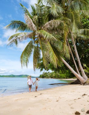 Asyalı kadınlar ve beyaz erkekler Koh Mak Tayland adasında palmiye ağaçlarıyla plajda dinleniyorlar. Palmiye ağaçları ve kumsalda beyaz kumlar 
