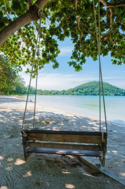 Salıncakta tropik bir plaj. Koh Mak tropik adası Tayland 'ın palmiye ağaçları arasındaki kumsalda sallanan bank..