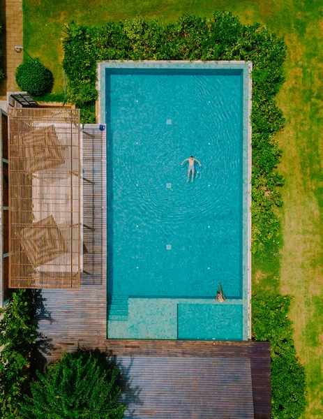 aerial drone view of a swimming pool in the jungle of Krabi Thailand, aerial view with a drone above swimming pool during a vacation in Thailand. . couple men and woman in pool from above