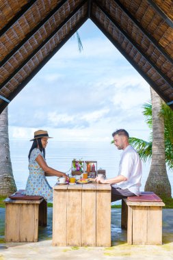 Tayland 'ın Koh Mak Adası' ndaki bir tatil sırasında kadınlar ve erkekler sahilde kahvaltı yapıyorlar. Plajda kahvaltı, palmiye ağaçları...