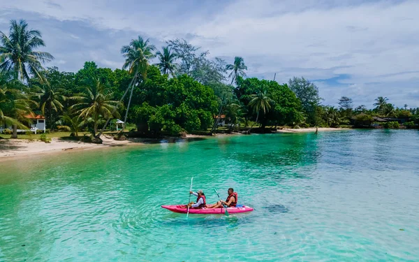 タイのコマック島のターコイズ色の海でカヤックの小道具を着た男性と女性 タイのヤシの木がある青い海と白いビーチでカヤックをしている男女 — ストック写真