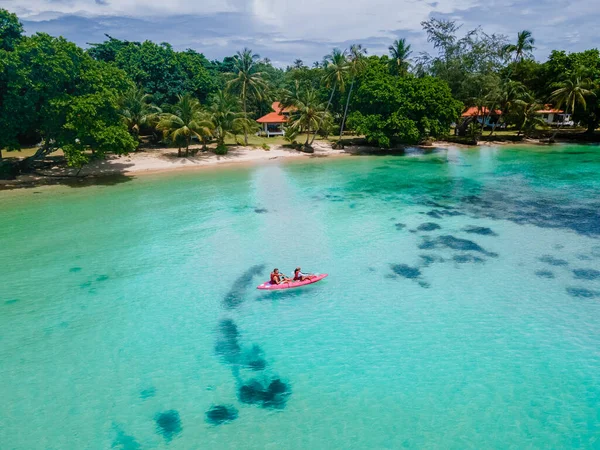 タイのコマック島のターコイズ色の海でカヤックの小道具を着た男性と女性 タイのヤシの木がある青い海と白いビーチでカヤックをしている男女 — ストック写真
