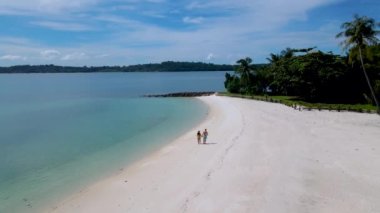 Koh Mak Tayland yakınlarındaki tropik adanın havadan görünüşü olan Koh Kham Trat Tayland 'da beyaz bir plajda yürüyen bir çift kadın ve erkek.. 