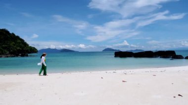 Koh Kham Trat Tayland 'da beyaz bir tropik plajda yürüyen Asyalı kadınlar, Koh Mak Tayland yakınlarındaki tropik adanın havadan görünüşü. Palmiye ağaçları ve beyaz kumlu plajı olan beyaz kumlu bir sahil.