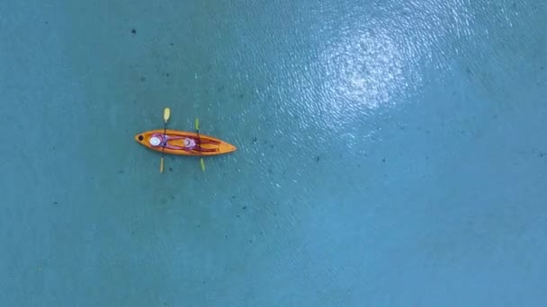 タイのコマック島のターコイズ色の海でカヤックの小道具を着た男性と女性 コマック島で休暇中の白人男性とアジア人女性のカップルタイ — ストック動画