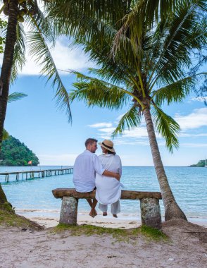 Günbatımında okyanus cephesinde şarap içen çift, okyanus sahilinin terasında kadın ve erkek. Erkekler ve kadınlar tatilde içki içiyorlar.