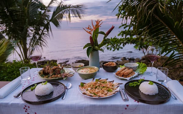 dinner table looking out over the ocean with Thai food, dinner during sunset. romantic dinner