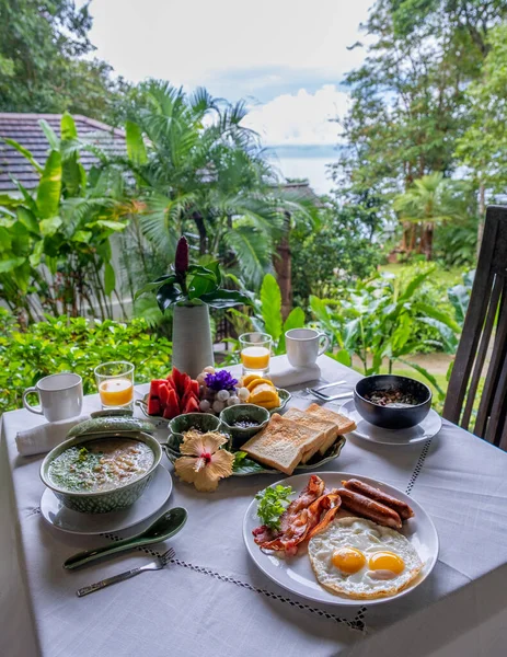 breakfast table in a tropical garden in Thailand, breakfast with Thai food, fruit, and eggs.