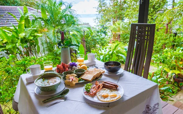 breakfast table in a tropical garden in Thailand, breakfast with Thai food, fruit, and eggs.