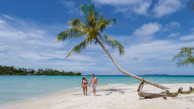 Koh Kood Tayland adasında palmiye ağaçları olan tropik bir sahil. Tayland 'da tatilde olan erkekler ve Asyalı Taylandlı kadınlar