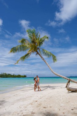 Koh Kood Tayland adasında palmiye ağaçları olan tropik bir sahil. Tayland 'da tatilde olan erkekler ve Asyalı Taylandlı kadınlar