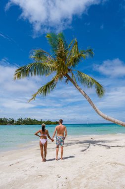 Koh Kood Tayland adasında palmiye ağaçları olan tropik bir sahil. Tayland 'da tatilde olan erkekler ve Asyalı Taylandlı kadınlar