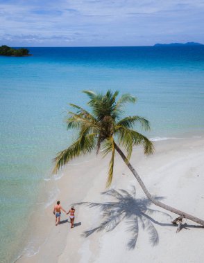 Koh Kood Tayland adasında palmiye ağaçları olan tropik bir sahil. Mavi okyanuslu beyaz tropik plaj. Tayland 'da tatilde olan birkaç erkek ve kadın. Yukarıdan insansız hava aracı görünüyor.
