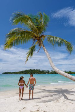 Koh Kood Tayland adasında palmiye ağaçları olan tropik bir sahil. Tayland 'da tatilde olan erkekler ve Asyalı Taylandlı kadınlar