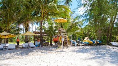 Koh Kood Tayland adasında palmiye ağaçları ve plaj korkulukları olan tropik bir sahil..