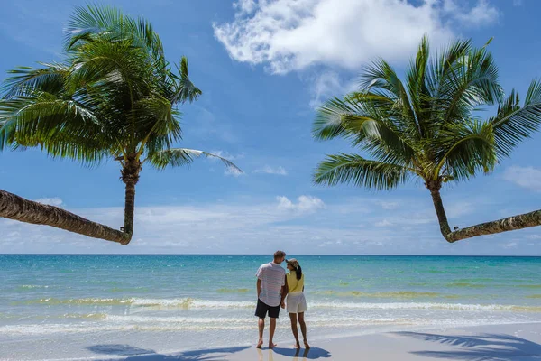 남자와 여자들은 야자나무가 해변을 해변에 야자나무를 매달아 대양의 남녀들 휴가를 — 스톡 사진