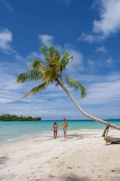 アジア系タイ人の女性と白人男性が熱帯のビーチにいて ヤシの木がある 青い海と白い熱帯のビーチにヤシの木をぶら下げ — ストック写真