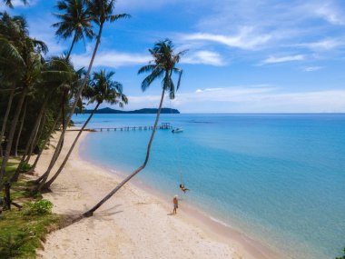 Bir çift Asyalı Taylandlı kadın ve Avrupalı erkek salıncaklı bir plajda, Koh Kood veya Koh Kut Tayland. 