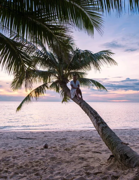 Tropik Koh Kood Adası veya Koh Kut Tayland. Gün batımında bir hurma ağacında dinlenen kadınlar.