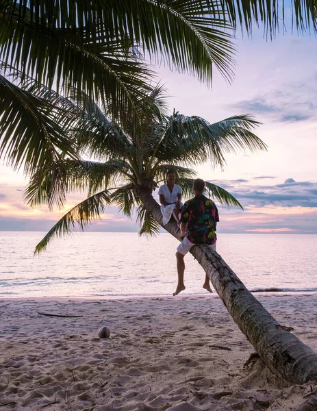 해변에 야자나무 위에서 휴식을 취하고 남녀들은 섬에서 휴가를 보내면서 일몰을 — 스톡 사진