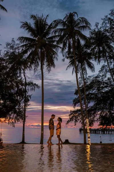 Пара Мужчин Женщин Тропическом Бассейне Пальмами Смотрящими Закат — стоковое фото