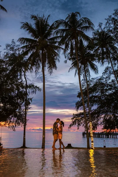 热带岛屿Koh Kood或Koh Kut Thailand 一对夫妻站在无限大的游泳池边 在巨大的棕榈树下观看日落 泰国妇女和高加索男子 — 图库照片