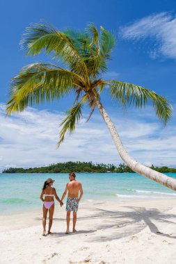Koh Kood Tayland adasında palmiye ağaçları olan tropik bir sahil. Tayland 'da tatilde olan erkekler ve Asyalı Taylandlı kadınlar