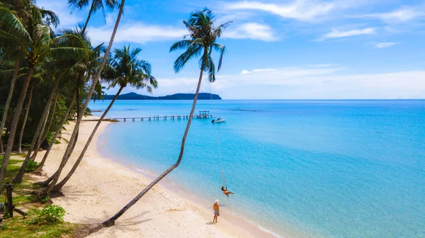 Bir çift Asyalı Taylandlı kadın ve Avrupalı erkek salıncaklı bir plajda, Koh Kood veya Koh Kut Tayland.