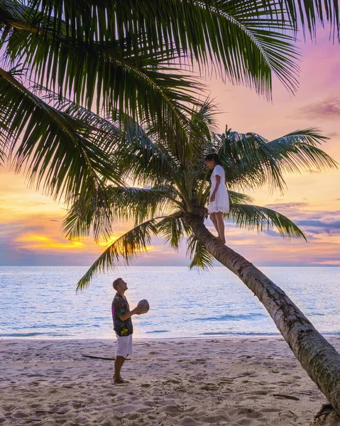 해변에 야자나무 위에서 휴식을 취하고 남녀들은 섬에서 휴가를 보내면서 일몰을 — 스톡 사진