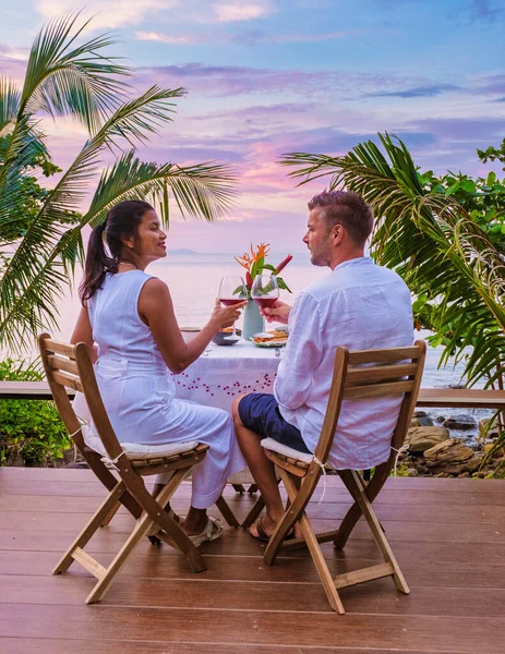 couple having romantic dinner by the ocean, dinner table looking out over the ocean with Thai food, dinner during sunset. romantic dinner in Thailand