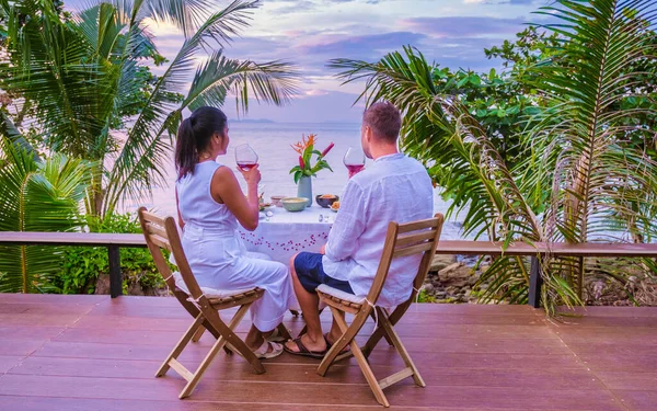 couple having romantic dinner by the ocean, dinner table looking out over the ocean with Thai food, dinner during sunset. romantic dinner in Thailand