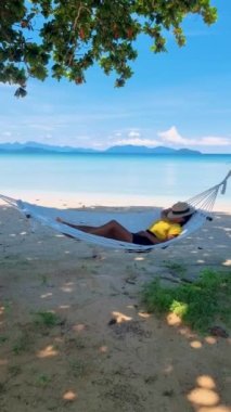 Koh Kood Tayland sahilinde bir hamakta dinlenen kadınlar