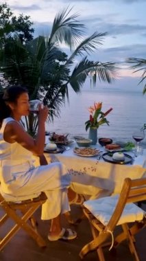 Gün batımında Tayland yemeğiyle sahilde romantik bir akşam yemeği, gün batımında Asyalı Taylandlı kadınlar akşam Koh Kood Tayland sahilinde akşam yemeği.