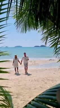 Koh Chang Tayland adasında tatilde olan birkaç erkek ve kadın. Mavi okyanuslu beyaz tropikal sahilde asılı palmiye ağaçları 