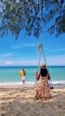 Koh Kood Tayland adasında bir çift kadın ve erkek salıncakta sallanırken kumsalda dinleniyorlar.