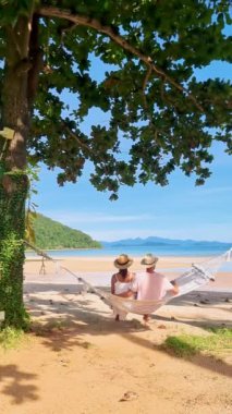 Koh Mka Tayland 'da tropik bir plajda hamakta bir çift kadın ve erkek.