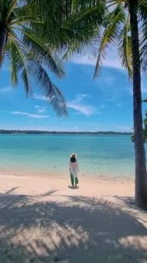 Koh Mak yakınlarındaki Koh Kham Tayland adasında tropikal bir plajda yürüyen Asyalı kadınlar.