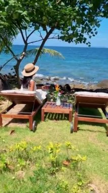 Asyalı kadınlar okyanusun kenarında şarap içerken, balayı sırasında lüks bir havuzda dinlenirken Koh Kood Tayland okyanusu manzaralı.