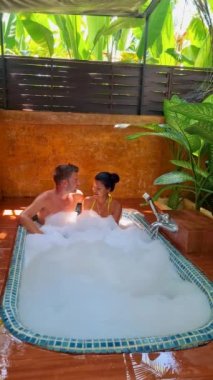 Tayland 'da tropikal bir bahçede banyo yapan bir çift erkek ve bir çift kadın ve erkekler açık hava orman tuvaletinde küvette.