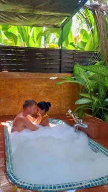 Tayland 'da tropikal bir bahçede banyo yapan bir çift erkek ve bir çift kadın ve bir küvet içinde açık orman tuvaletinde kadınlar.