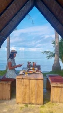 Koh Mak Tayland sahilinde kahvaltı yapan Asyalı kadınlar. Taylandlı kadınlar sahilde lüks bir kahvaltı yapıyorlar.