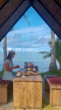 Koh Mak Tayland sahilinde kahvaltı yapan Asyalı kadınlar. Taylandlı kadınlar sahilde lüks bir kahvaltı yapıyorlar.