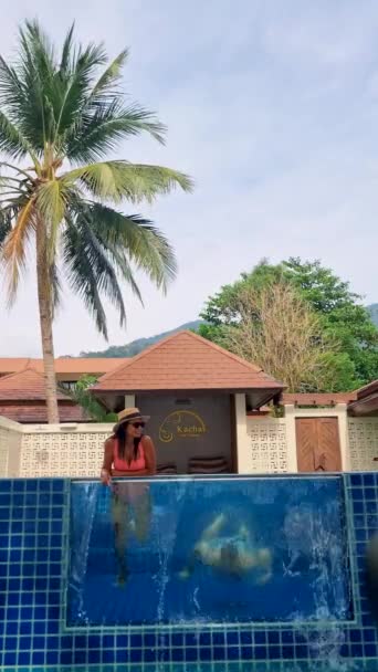 一对男女情侣在豪华度假期间在他们的游泳池别墅前放松一下 — 图库视频影像