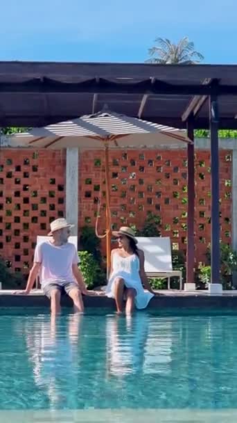 熱帯の島で休暇中にスイミングプールにいた若い男女のカップル 日没時にインフィニティプールの男と女 タイでの贅沢な休暇 — ストック動画