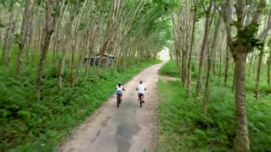 A couple of men and women on a bicycle at a rubber plantation in Thailand. 