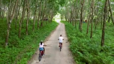 A couple of men and women on a bicycle at a rubber plantation in Thailand. 