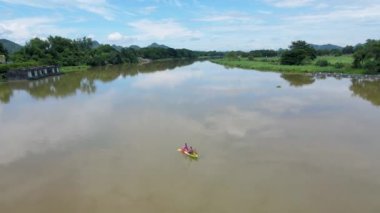 A couple of men and women in kayak on the River Kwai in Thailand. men and women peddling in a kayak on the river in Thailand