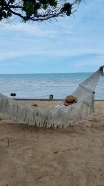 Hua Hin Tayland 'da bir hamakta güneşin doğuşunu izleyen kadınlar. Huahin Tayland sahilindeki hamakta yaşayan Asyalı kadınlar.