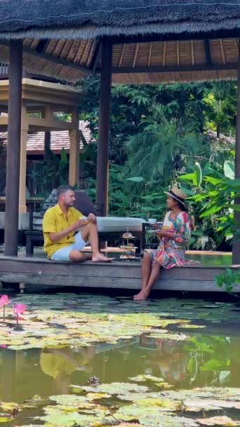 下午茶在一个池塘里 茶在泰国的一个热带花园里 一对夫妇在热带花园里喝着高茶 — 图库视频影像